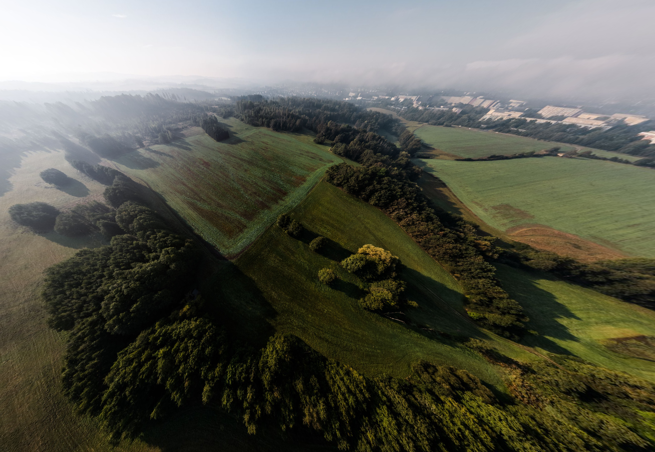 Luftaufnahme einer hügeligen vogtländischen Landschaft im Morgennebel.